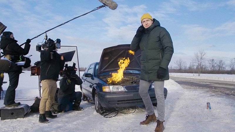 Alex Lapointe standing in front of a burning car